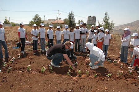 Ryan and children planting a peace sign garden at Al-Aqaba.